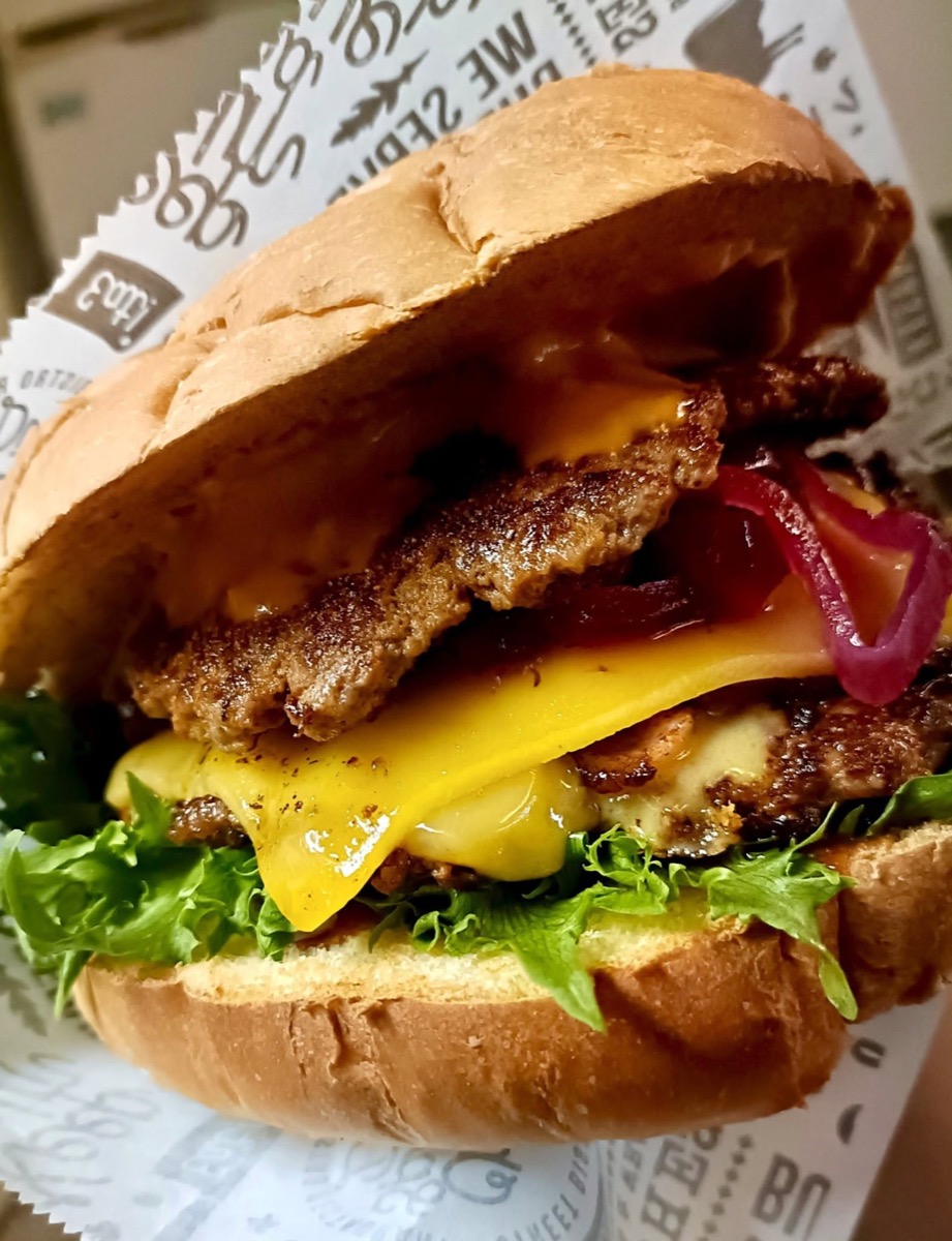 Mehevä smash-burgeri: kaksi pihviä, sulanutta cheddaria, punasipulia ja salaattia